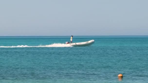 Морський пейзаж з хвилястою поверхнею блакитної морської води з білим швидкісним човном, що швидко плаває на спокійних хвилях — стокове відео