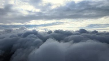Dünya 'nın yüksek irtifasında, yağmur fırtınasından önce oluşan kabarık kümülüs bulutlarıyla kaplı uçak penceresinden hava görüntüsü