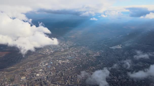 Luchtfoto vanuit vliegtuigraam op grote hoogte van verre stad bedekt met gezwollen cumulus wolken vormen zich voor regenbui — Stockvideo