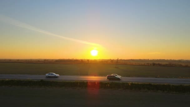 Vista aerea di strada interurbana con auto guida veloce al tramonto. Vista dall'alto dal drone del traffico autostradale in serata — Video Stock