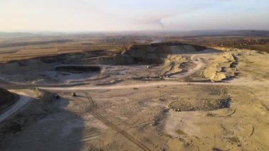 Kazı makineleri ve çöp kamyonlarıyla inşaat endüstrisi için kumtaşı malzemelerinden oluşan açık maden manzarası. Madencilik ve kullanışlı mineral üretiminde ağır ekipman