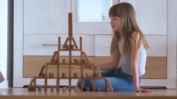 高い建物の構造に木製のおもちゃのブロックを積み重ねるゲームで遊ぶ創造的な子供の女の子。手の動き制御と集中力の概念 — ストック動画