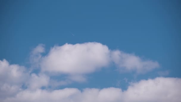 Avión a reacción de pasajeros lejano volando a gran altitud en el cielo azul con nubes blancas dejando rastro de humo de la estela detrás. Concepto de viaje aéreo — Vídeos de Stock