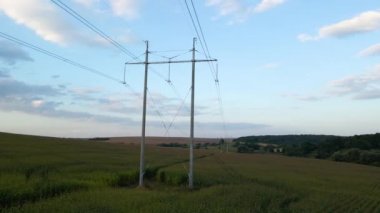 Yeşil tarımsal alanlar arasında elektrik kabloları olan yüksek voltaj kulesi. Elektrik konsepti aktarımı