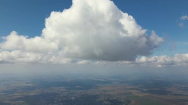 Dünya 'nın yüksek irtifasındaki uçak penceresinden hava manzarası beyaz kabarık kümülüs bulutlarıyla kaplı.