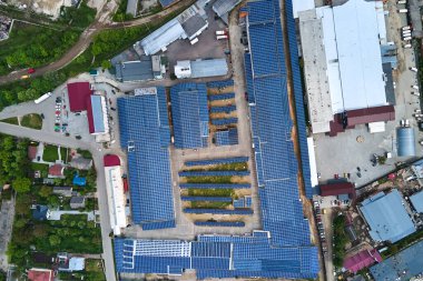 Sanayi binasının çatısına yeşil ekolojik elektrik üretmek için monte edilen mavi fotovoltaik güneş panellerinin hava görüntüsü. Sürdürülebilir enerji konsepti üretimi.