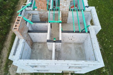 Havalandırılmış hafif beton duvarları ve inşaat halindeki ahşap çatı kirişleri olan bitmemiş özel evin havadan görüntüsü..