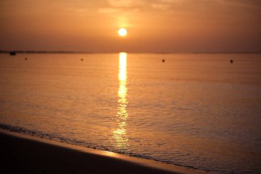 Sakin deniz kıyısı, kumlu sahilde güneş doğarken ezici dalgalar..