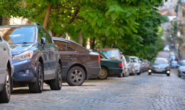 Sokak kenarında park halindeki arabalarla şehir trafiği.