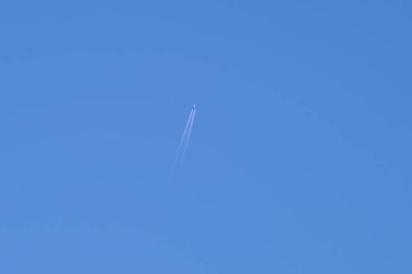 Mesafeli yolcu jet uçağı açık mavi gökyüzünde yüksek irtifada uçarken ardında beyaz duman izi bırakıyor. Hava taşımacılığı kavramı.