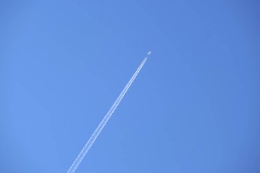 Mesafeli yolcu jet uçağı açık mavi gökyüzünde yüksek irtifada uçarken ardında beyaz duman izi bırakıyor. Hava taşımacılığı kavramı.