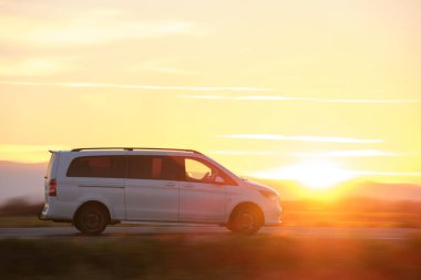 Yolcu kamyonu gün batımında şehirlerarası yolda hızla gidiyor. Akşamları otoyol trafiği.