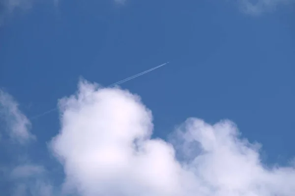 遠くの旅客機は白い雲が後ろの輪郭の煙の跡を残す青い空の高い高度で飛んでいる 航空旅行の概念 — ストック写真