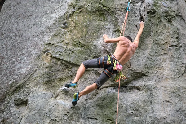 若い男岩の山の急な壁を登る 男性登山者は困難なルートを克服します 極端なスポーツの概念に従事 — ストック写真