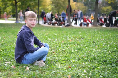 Çimlerin üzerinde dinlenen çocuk portresi.