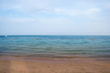 Mavi deniz suyunun yüzeyi ve küçük dalgalı dalgaların sarı kumsala çarptığı deniz burnu. Seyahat ve tatil kavramı.