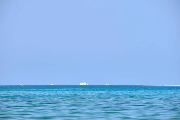 穏やかな波に浮かぶ遠くの船と青い海の水の波紋の表面を持つ風景 — ストック写真