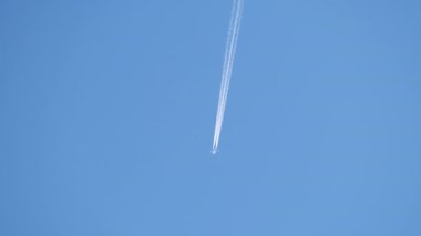 Mesafeli yolcu jet uçağı açık mavi gökyüzünde yüksek irtifada uçarken ardında beyaz duman izi bırakıyor. Hava taşımacılığı kavramı