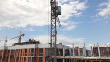 İnşaat halindeki yüksek beton binadaki vinç ve işçiler. Gayrimenkul geliştirme kavramı