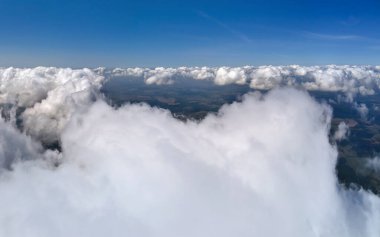 Dünya 'nın yüksek irtifasında, yağmur fırtınasından önce oluşan kabarık kümülüs bulutlarıyla kaplı uçak penceresinden hava görüntüsü