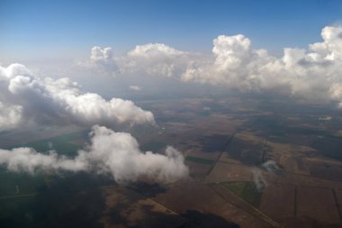 Parlak güneşli bir günde beyaz bulutların uçak penceresinden hava manzarası