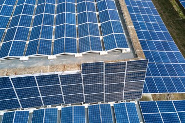 Sanayi binasının çatısına yeşil ekolojik elektrik üretmek için monte edilen mavi fotovoltaik güneş panellerinin hava görüntüsü. Sürdürülebilir enerji konsepti üretimi