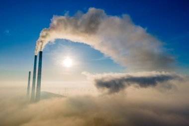 Kömür santralinin hava manzarası siyah dumanlı yüksek borular gün batımında atmosferi kirletiyor