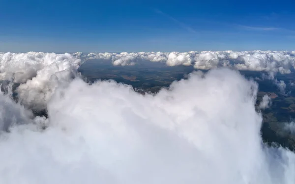 Vista aérea da janela do avião em alta altitude da terra coberta com nuvens cumulus inchadas que se formam antes da tempestade — Fotografia de Stock