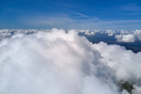 Vista aérea desde la ventana del avión a gran altitud de la tierra cubierta de nubes de cúmulos hinchados que se forman antes de la tormenta —  Fotos de Stock