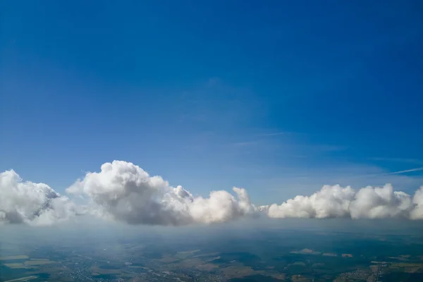 Aerial view from airplane window at high altitude of earth covered with white puffy cumulus clouds — Stock Photo, Image