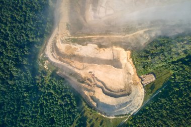 Kazı araçları ve çöp kamyonları ile inşaat endüstrisi için kireçtaşı malzemelerinin açık çukur madenciliğinin hava görüntüsü