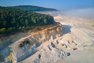 Kazı araçları ve çöp kamyonlarıyla inşaat endüstrisi için kireçtaşı malzemelerinin açık maden sahası görüntüsü
