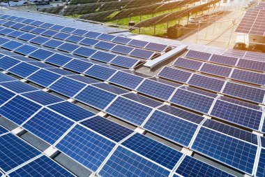 Sanayi binasının çatısına yeşil ekolojik elektrik üretmek için monte edilmiş mavi fotovoltaik panelli güneş enerjisi santralinin hava görüntüsü. Sürdürülebilir enerji konsepti üretimi