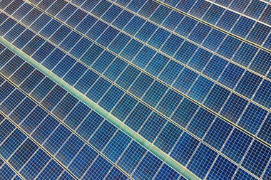 Temiz ekolojik elektrik üretmek için çatıya monte edilen mavi fotovoltaik güneş panellerinin havadan görünüşü. Yenilenebilir enerji konsepti üretimi