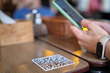 Konuk elin restoranda yemek sipariş ederken çevrimiçi menü için qr kodunu cep telefonuyla taraması