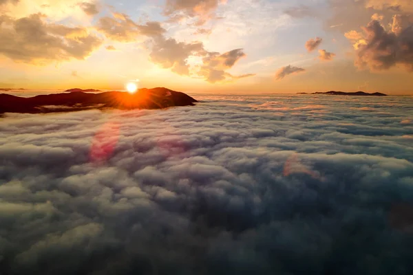Αεροφωτογραφία της ζωντανής ανατολής πάνω από λευκά πυκνά σύννεφα με μακρινά σκοτεινά βουνά στον ορίζοντα — Φωτογραφία Αρχείου