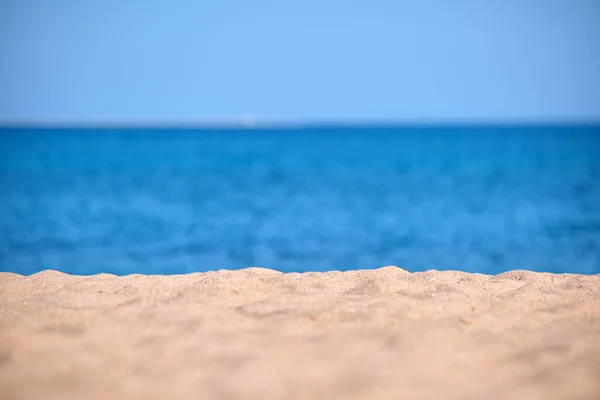 Close up de superfície de areia amarela limpa cobrindo praia à beira-mar com água do mar azul no fundo. Conceito de viagem e férias — Fotografia de Stock