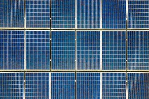 Primer plano de la superficie de los paneles solares fotovoltaicos azules montados en el techo del edificio para producir electricidad ecológica limpia. Concepto de producción de energías renovables —  Fotos de Stock