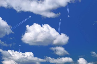 Many distant passenger jet planes flying on high altitude on clear blue sky leaving white smoke trace of contrail behind. Busy air transportation concept clipart
