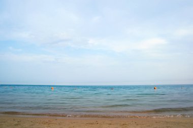 Mavi deniz suyunun yüzeyi ve küçük dalgalı dalgaların sarı kumsala çarptığı deniz burnu. Seyahat ve tatil kavramı