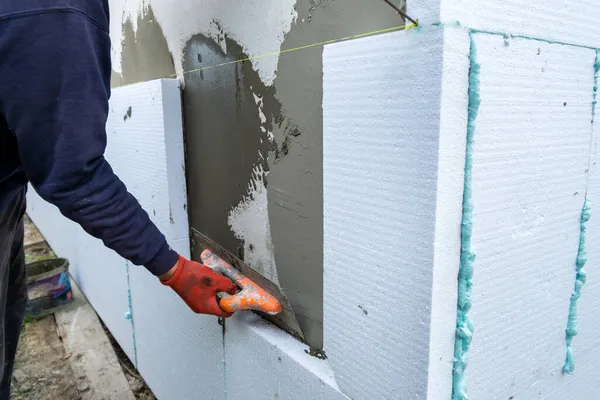 Robotnik budowlany montujący blachy styropianowe na ściance fasady domu w celu ochrony termicznej — Zdjęcie stockowe
