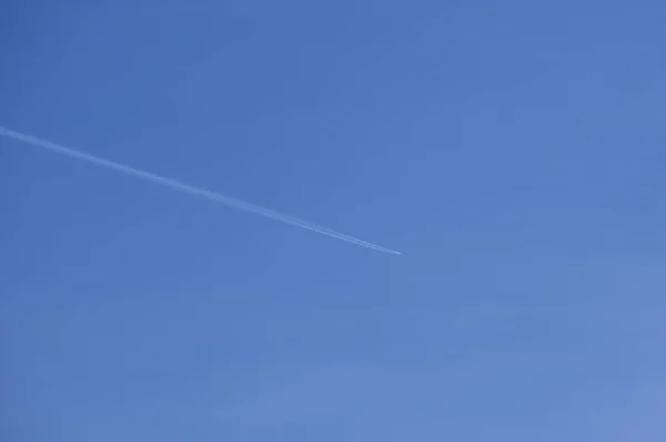 遠くの旅客機は、澄んだ青い空に高い高度を飛んで、白い煙の跡を後ろに残しています。航空交通の概念 — ストック写真
