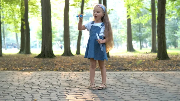 Little szczęśliwy dziecko dziewczyna dmuchanie bańki mydlane na zewnątrz w letnim parku — Zdjęcie stockowe
