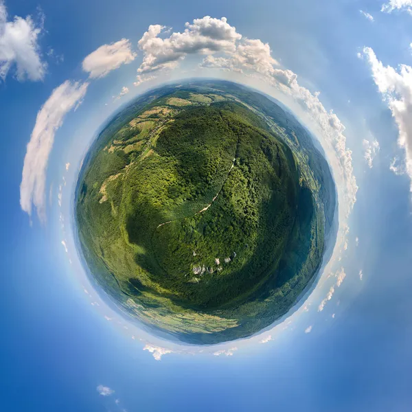 Mała planeta globus z ciemnymi wzgórzami górskimi pokryte zieloną sosną mieszaną i bujne lasy otoczone jasnym błękitnym niebem z białymi chmurami — Zdjęcie stockowe