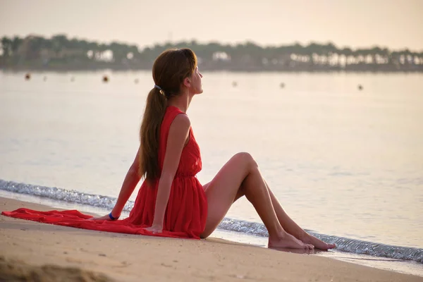 Solitario giovane donna seduta sulla spiaggia di sabbia oceanica dal mare godendo calda serata tropicale — Foto Stock