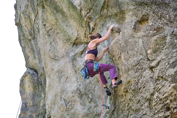 Forte alpinista do sexo feminino escalada parede íngreme de montanha rochosa. Desportista superando rota difícil. Envolvendo-se em conceito de passatempo esportivo extremo — Fotografia de Stock