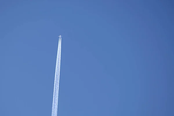 Afstand passagiersvliegtuig vliegen op grote hoogte op heldere blauwe lucht laat witte rook spoor van contrail achter. Luchtvervoersconcept — Stockfoto
