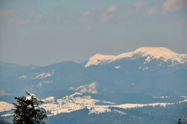 Soğuk kış günlerinde yoğun kar yağışı sonrası yüksek dağlık tepelerle kaplanmış kış manzarası.
