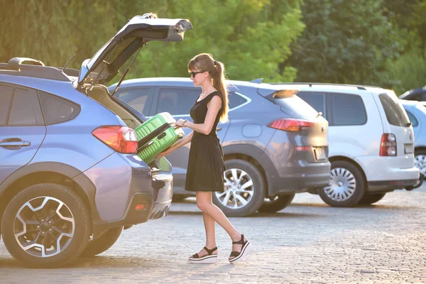 Joven conductora cargando la maleta de equipaje dentro de su coche. Concepto de viajes y vacaciones — Foto de Stock