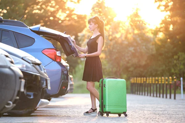 Joven conductora sacando una maleta de equipaje de su auto. Concepto de viajes y vacaciones — Foto de Stock